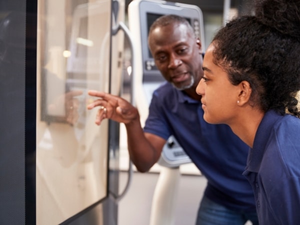 Un apprendista e un tutor discutono davanti a un macchinario in azienda