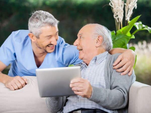 colf o badante uomo sorride ad un signore di cui si prende cura