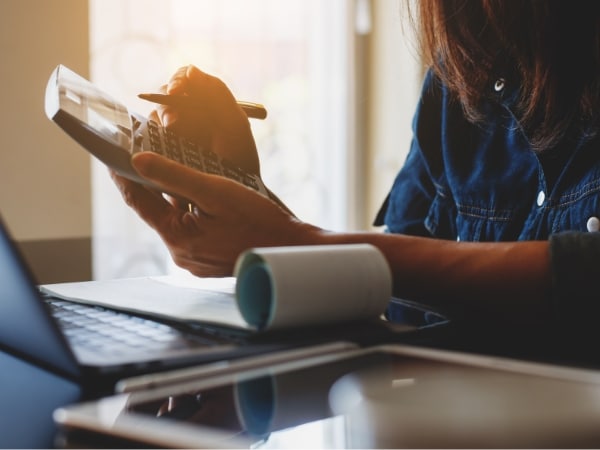 Persona che utilizza una calcolatrice per verificare errori di calcolo in busta paga