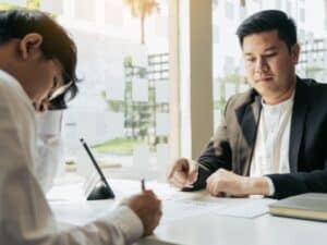 Persona che firma un documento di fronte a un consulente, relativo all'indennità sostitutiva di preavviso.