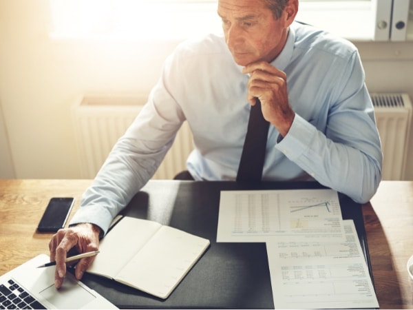 Un consulente del lavoro esamina documenti e lavora al computer, con una calcolatrice e buste paga sulla scrivania.