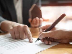 Due professionisti seduti ad un tavolo mentre uno di loro spiega il contratto di fornitura servizio