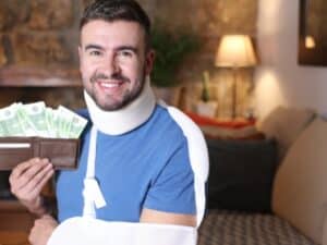 Un uomo con un infortunio sul lavoro tiene in mano un portafoglio pieno di soldi, simboleggiando l'indennità INAIL