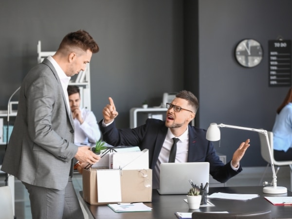 un lavoratore dipendente sta alzando un dito e sembra litigare con il suo datore di lavoro, gesto di insubordinazione del lavoratore.