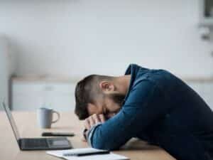 Un uomo appoggia la testa sulla scrivania, simbolo dello stress legato al licenziamento ad nutum.