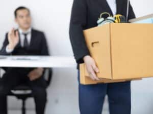 Un dipendente lascia l'ufficio con una scatola, rappresentando le dimissioni