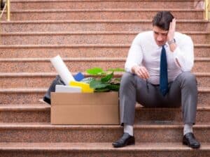 Un dipendente appare sconsolato seduto su gradini per licenziamento senza preavviso