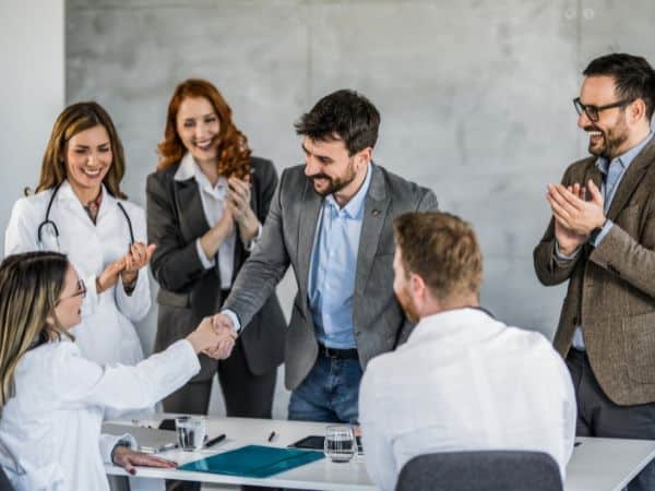 un ragazzo viene elogiato da un gruppo di altre persone per essere stato assunto